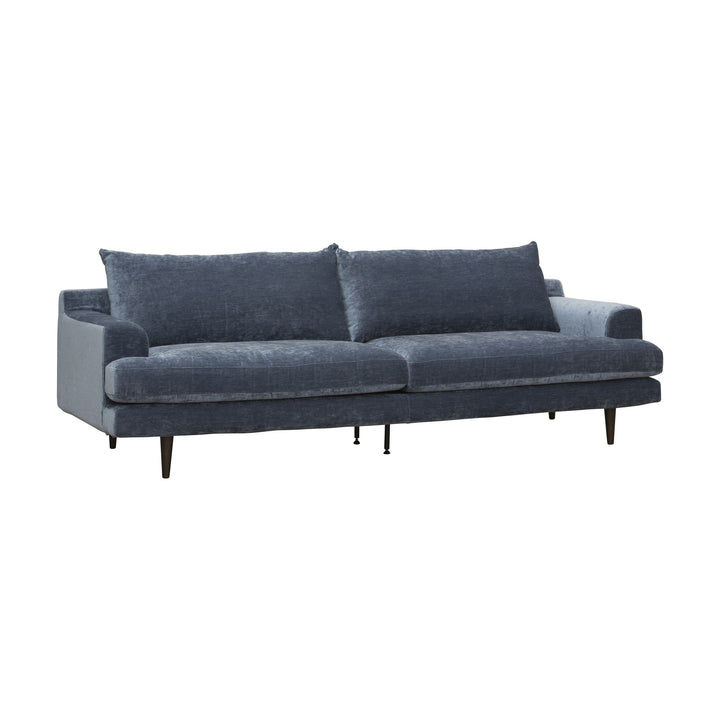 Leon sofa i blå chenille med løse rygg- og seteputer og mørke ben, sett skrått mot hvit bakgrunn.