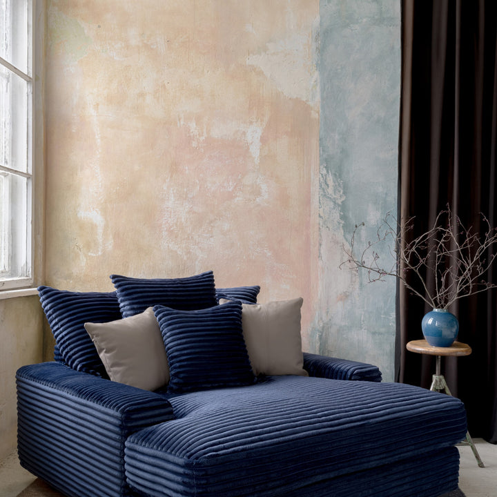 Tuva Xdeep daybed i mørk blå kordfløyel i rom med plastervegg, mørk gardin og sidebord med vase.