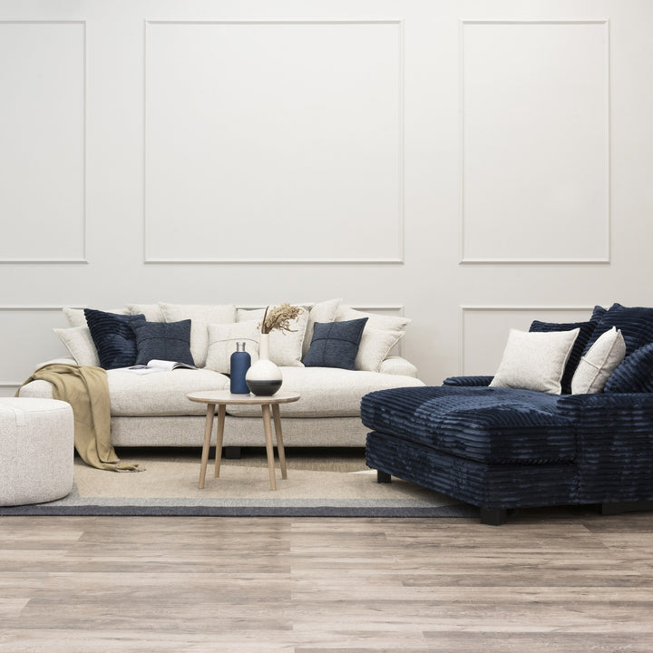 Tuva Xdeep i lys beige strukturstoff med mørk blå kordfløyel-daybed i stue med puff og sidebord.