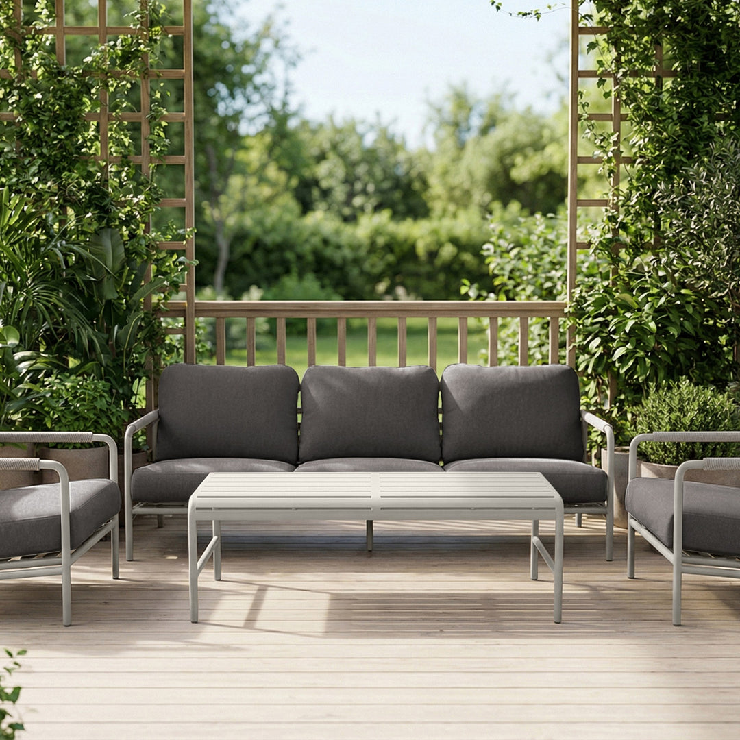 Cantos sofagruppe med mørk grå puter og hvit ramme i frodig hagemiljø med espalier og grønt