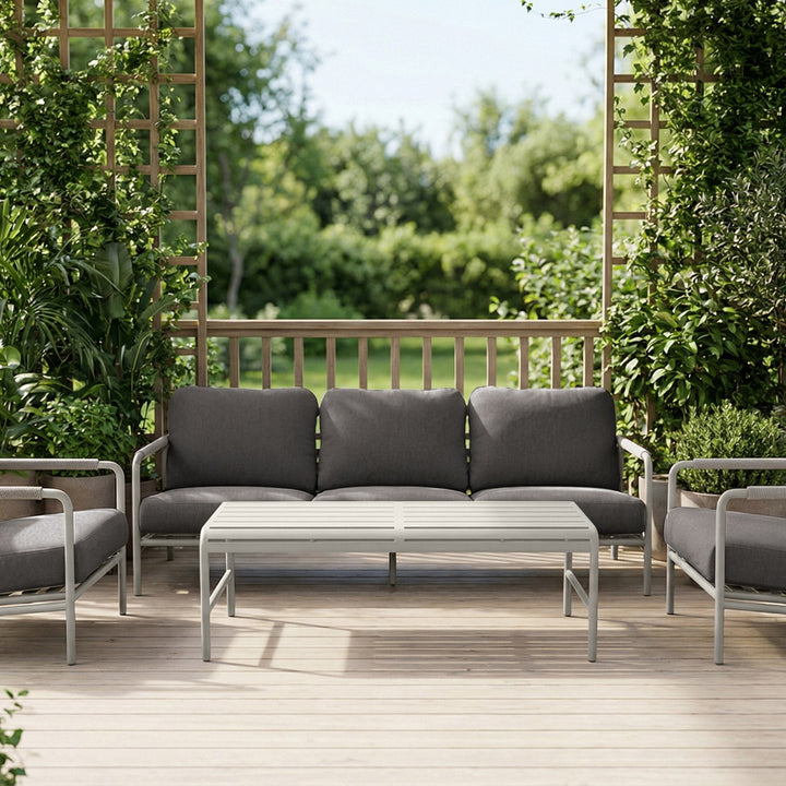 Cantos sofagruppe med mørk grå puter og hvit ramme i frodig hagemiljø med espalier og grønt