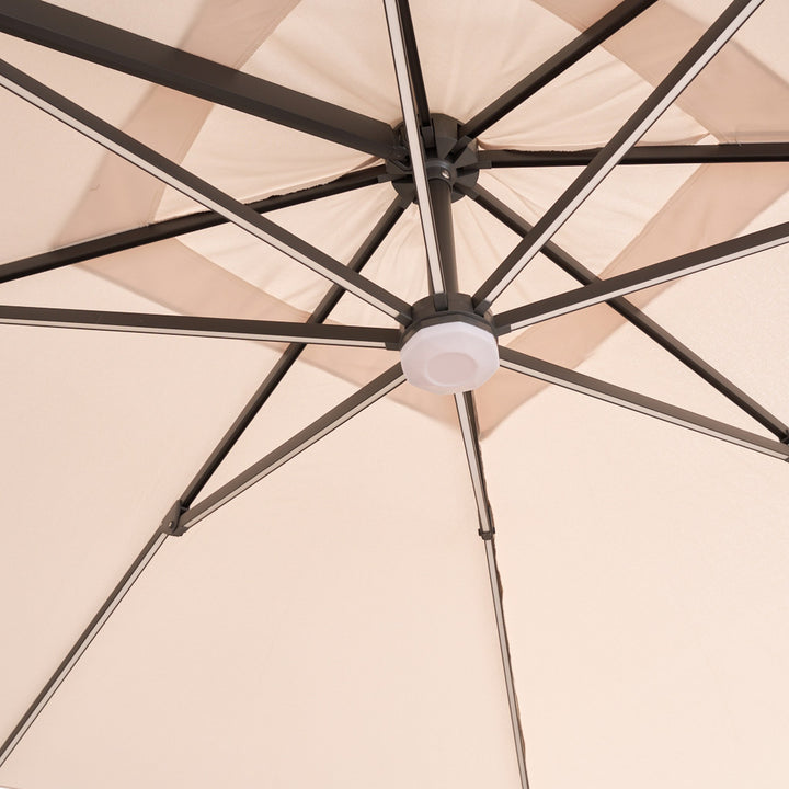 Trattoria parasoll i beige, underside med ribber og hvit LED-lampe i navet sett nedenfra