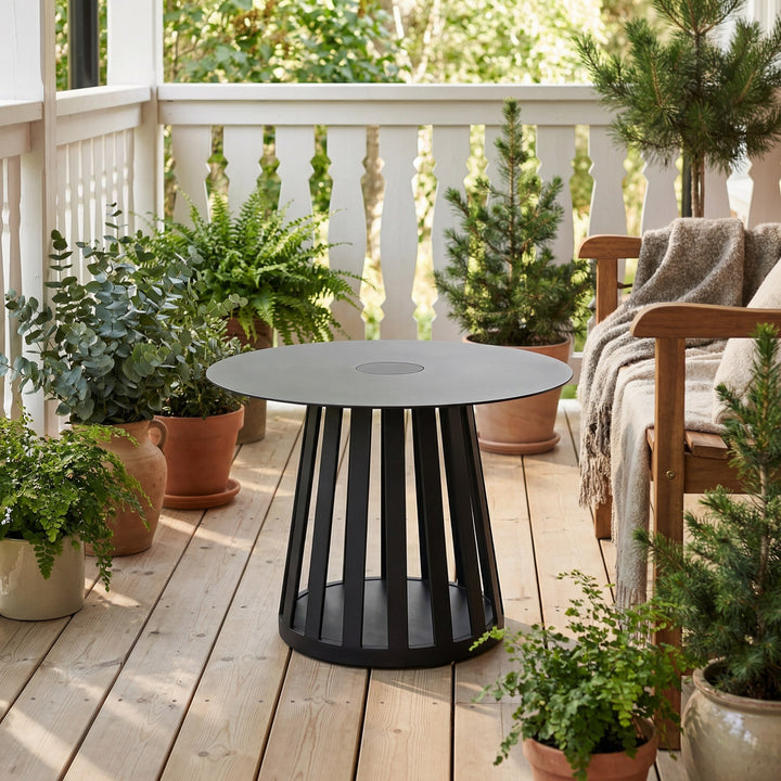 Trento sofabord i sort, rundt med spilebunn på en terrasse med potteplanter og pledd