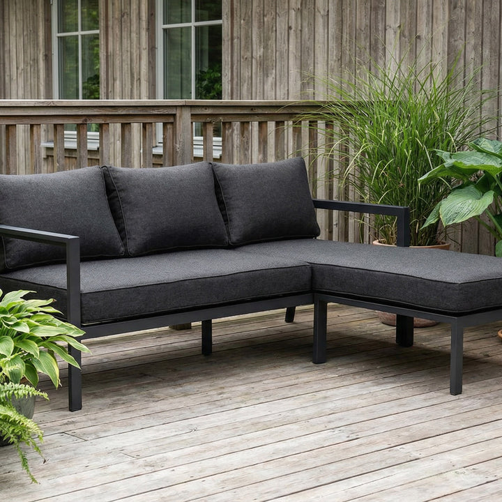 Brafab Delia utesofa i sort med antrasitt puter, på terrasse med grønne planter og tregjerde