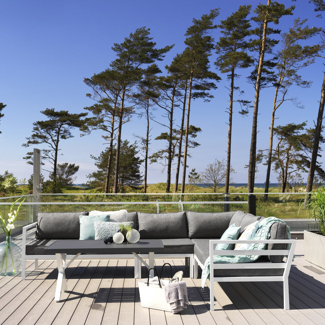 Brafab Weldon utesofa med hvit ramme og grå puter, mintgrønne pynteputer, terrasse ved sjø med furu