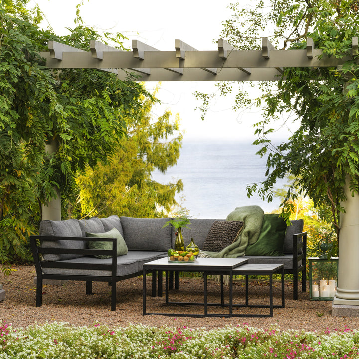 Brafab Weldon utesofa med sort ramme og grå puter, grønne pynteputer, under pergola med havutsikt