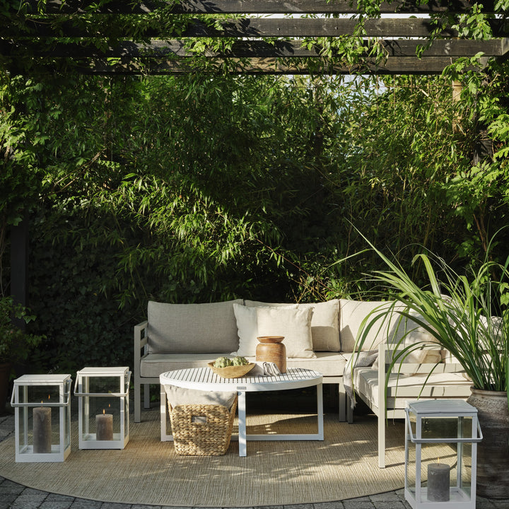 Brafab Weldon utesofa i beige med hvit ramme under pergola med lykter og grønne planter