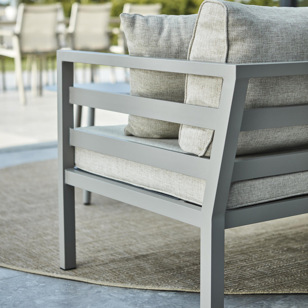 Brafab Weldon utesofa, nærbilde av grå ramme og beige pute på teppe ute