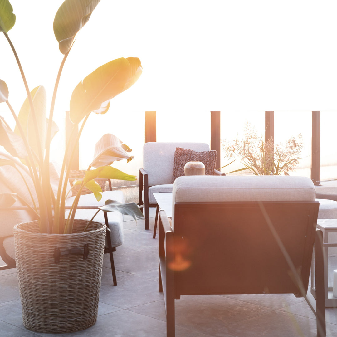 Brafab Lyra hagestol med beige puter og sort ramme på terrasse i solnedgang med stor plante