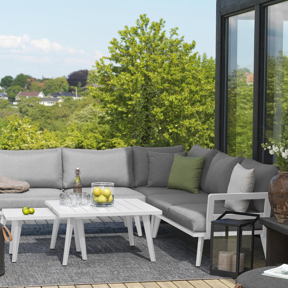 Brafab Villac ryggpute i grått på utesofa med hvit ramme, terrasse med grønn utsikt og lykt