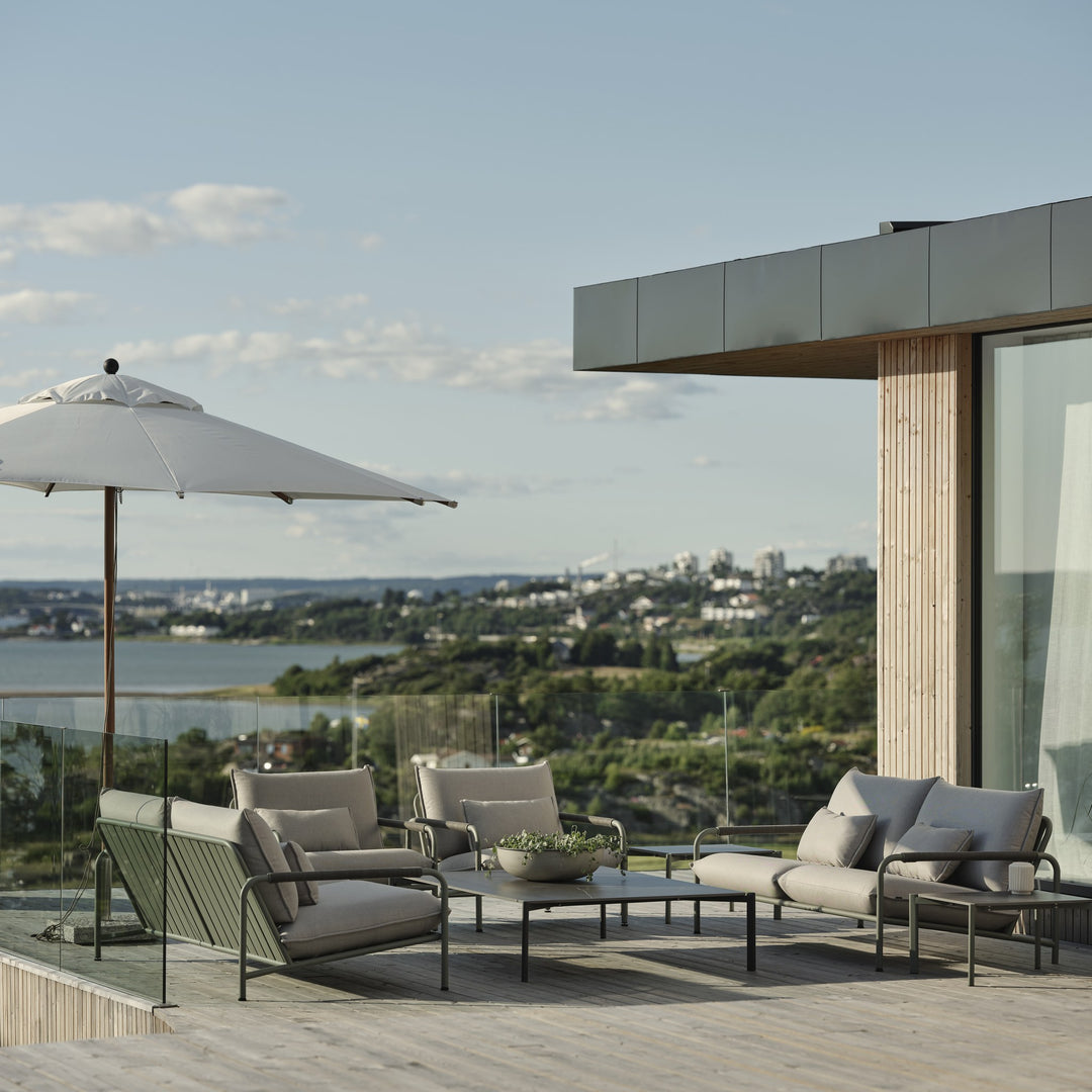 Brafab Lerberget loungegruppe under hvit parasoll på terrasse med utsikt over fjord og åser