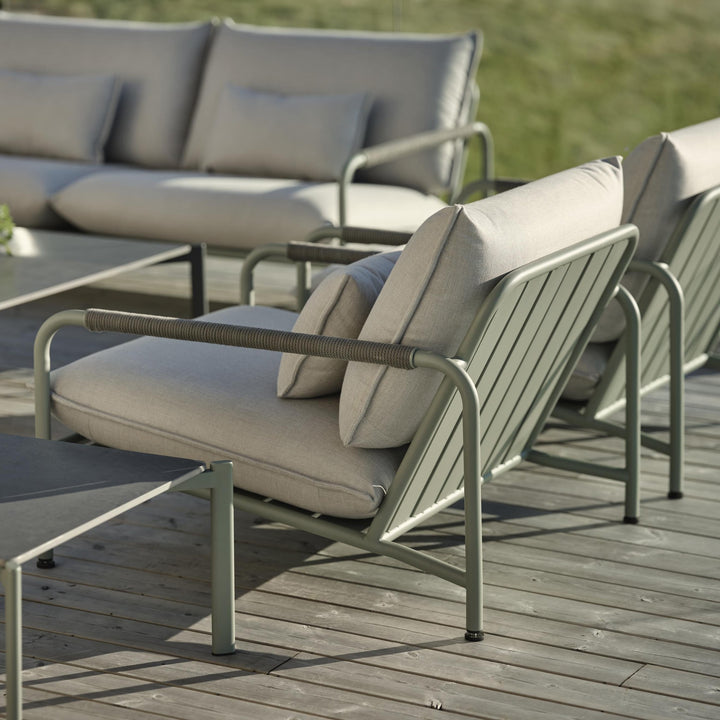 Brafab Lerberget hagestol i dusty green med grå puter på terrasse, utesofa i bakgrunnen