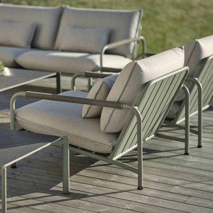 Brafab Lerberget hagestol i dusty green med grå puter på terrasse, utesofa i bakgrunnen