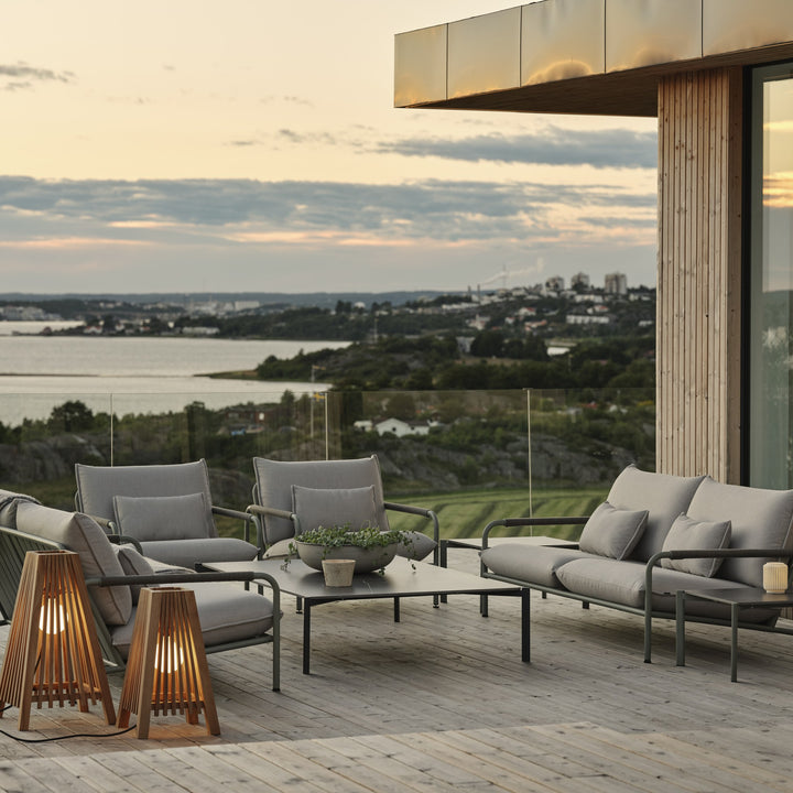 Brafab Lerberget loungeserie i dusty green på terrasse i skumring med trelykter og sjøutsikt