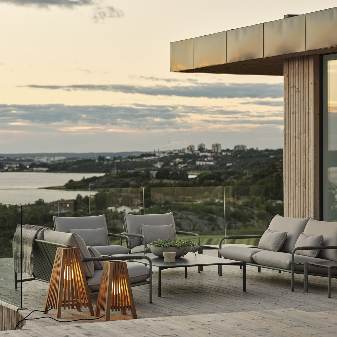 Brafab Lerberget loungeserie i dusty green på terrasse i solnedgang med pledd, trelykter og sjøutsikt
