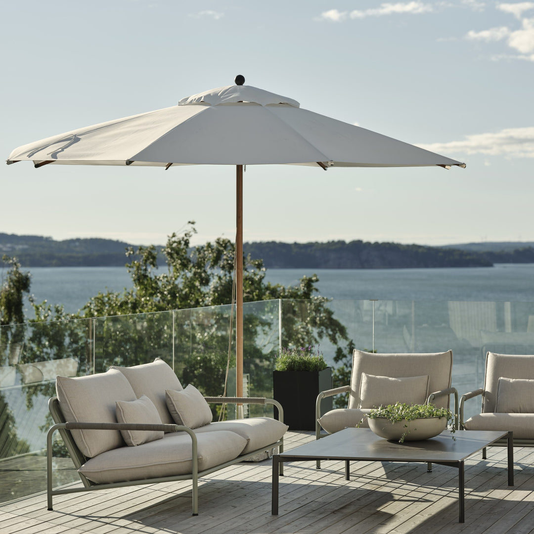 Brafab Lerberget utesofa med støvgrønn ramme og lyse puter under parasoll, terrasse med havutsikt