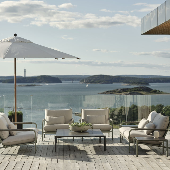 Brafab Lerberget utesofa i dusty green med lyse puter på terrasse med havutsikt