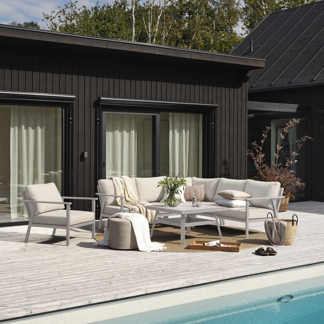 Brafab Samvaro modulsofa med lys ramme og beige puter på terrasse ved sort hus og basseng
