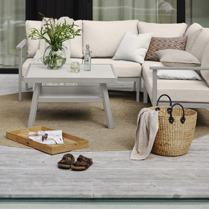 Brafab Samvaro Lounge modulsofa i beige med lysegrå ramme, hvitt bord, blomster og kurv på terrasse