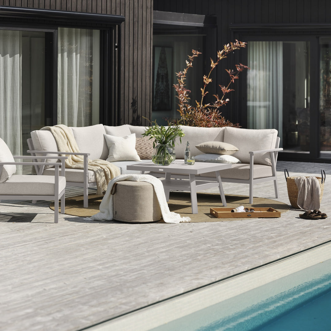 Brafab Samvaro Lounge modulsofa i beige med lysegrå ramme, hvitt bord og puff ved basseng