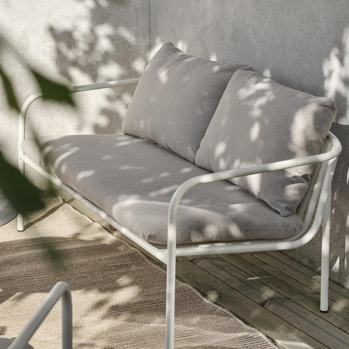 Brafab Bendt sofa med hvit ramme og gråbeige puter på balkong med solflekker og tredekke