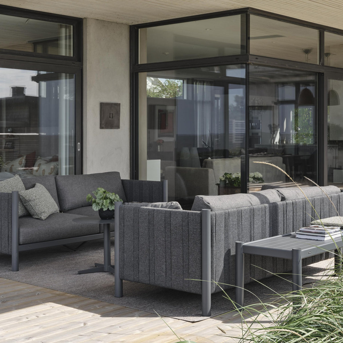 Brafab Brad loungesofa i antrasitt med grå puter på terrasse ved hus med store glassflater