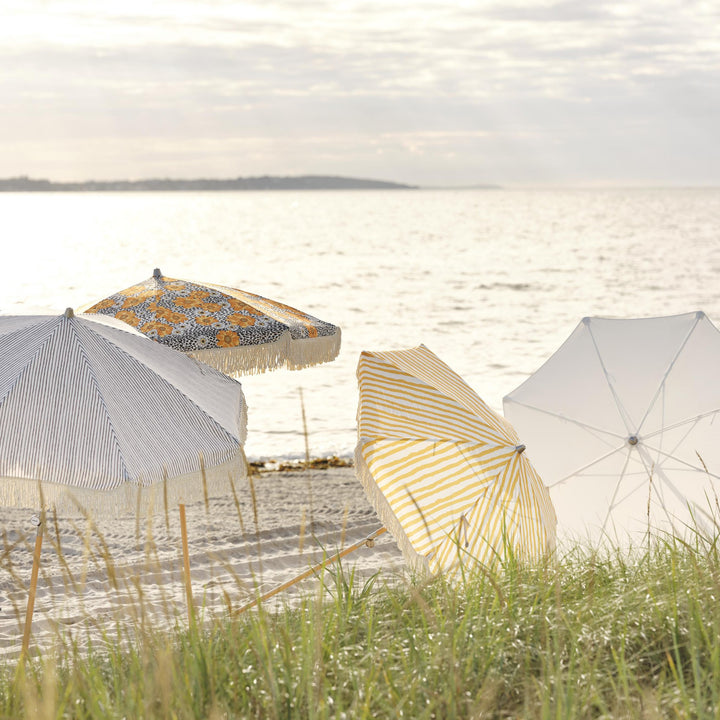 Brafab Gatsby parasoll med gule blomster og frynser på stranden ved sjøen