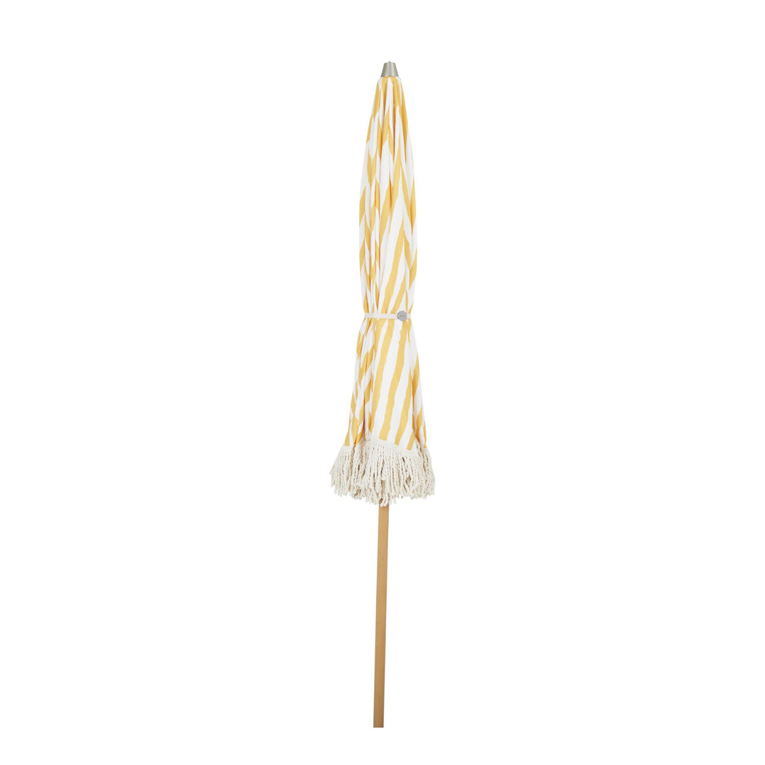 Brafab Gatsby parasoll sammenslått, gulstripet stoff med frynser og trestolpe mot hvit bakgrunn