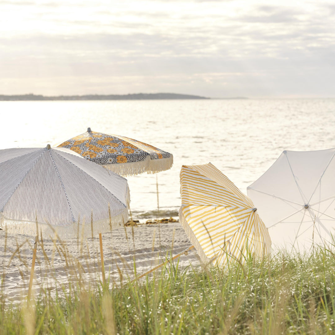Brafab Gatsby parasoll med gule striper blant flere parasoller på strand ved sjøen
