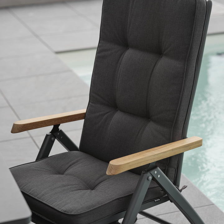 Brafab Andy spisestol med sort tekstil og teak armlener, sett bakfra ved basseng