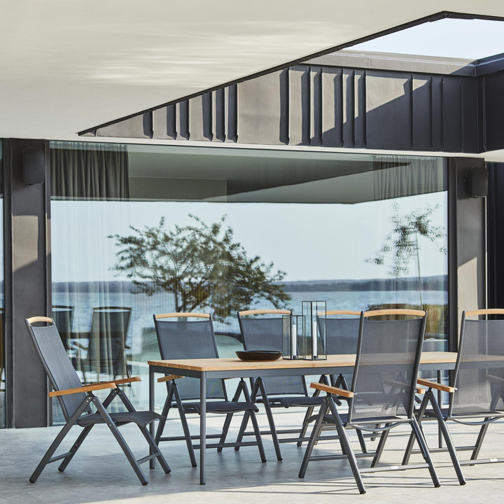 Brafab Andy spisestol i antrasitt tekstil ved teakbord på terrasse med havutsikt