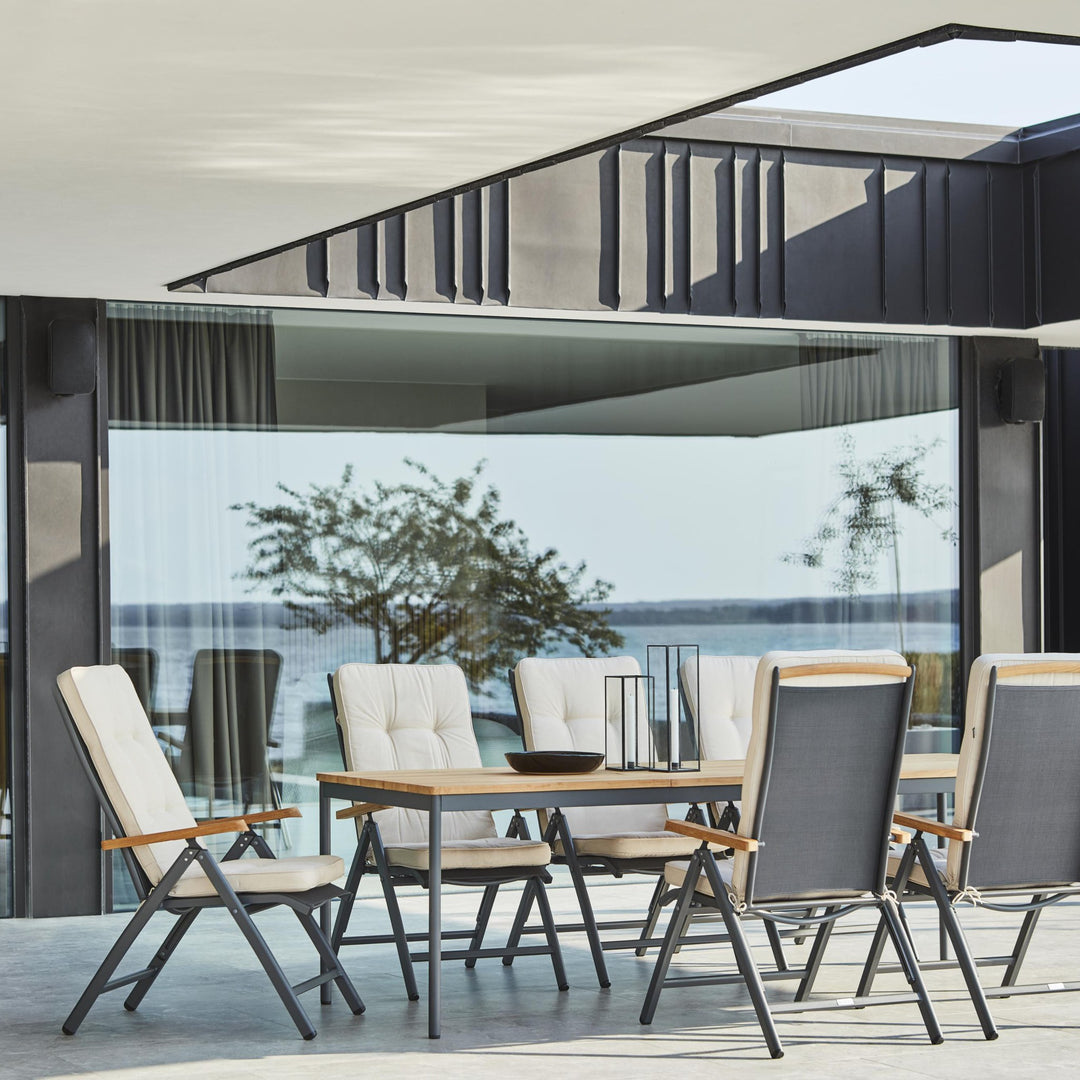 Brafab Andy spisestol i antrasitt med puter ved teakbord på overbygd terrasse ved sjøen