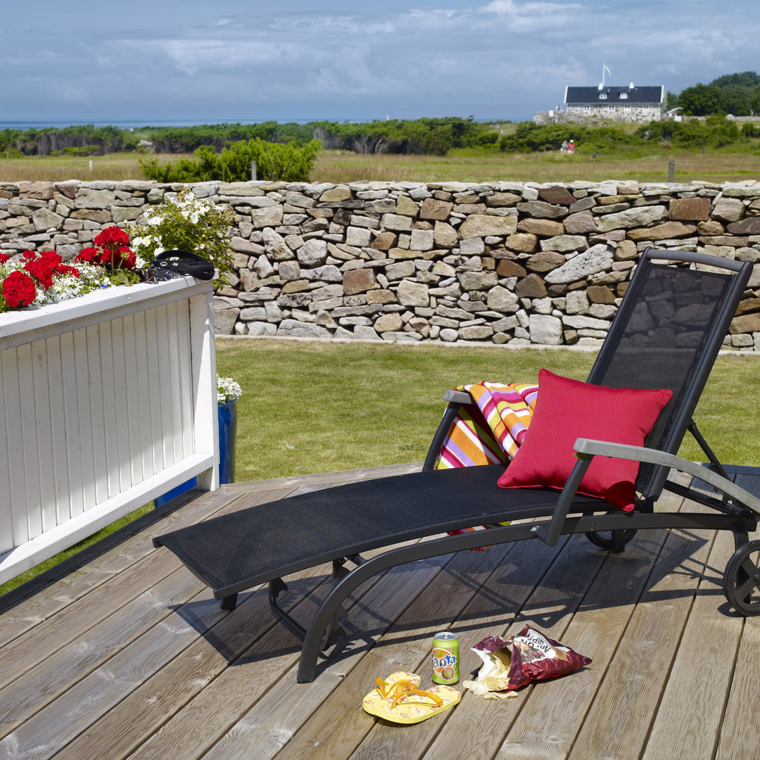 Brafab Andy solseng i sort tekstil med rød pute på terrasse ved steinmur og hav
