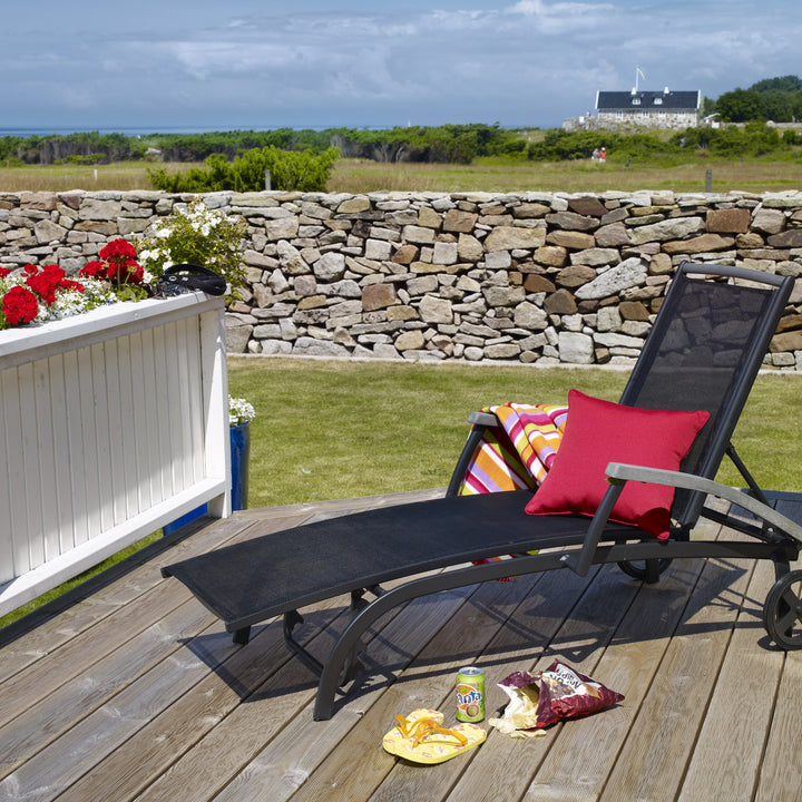 Brafab Andy solseng i sort tekstil med rød pute på terrasse ved steinmur og hav
