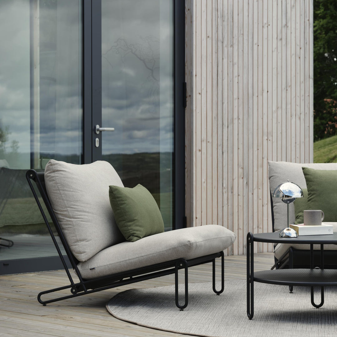 Brafab Blixt hagestol i sort med beige puter på terrasse, grønn pute og svart sidebord