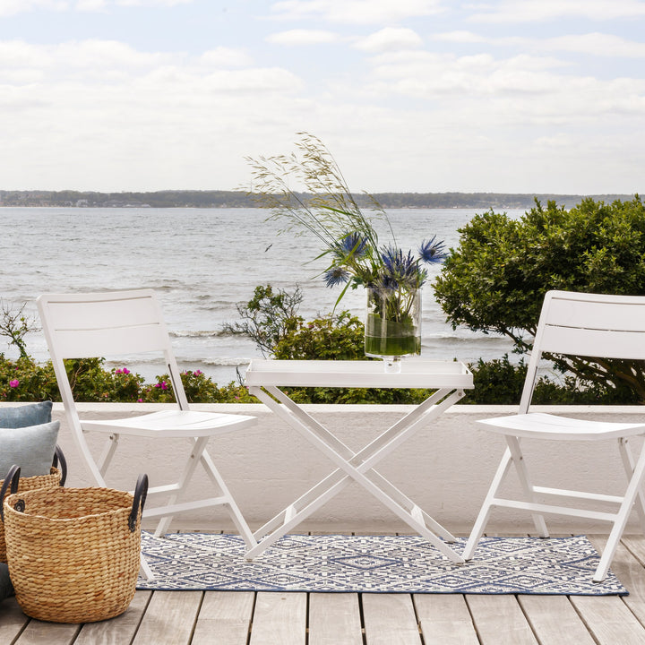 Brafab Wilkie klappstol i hvit, to stoler med klappbord på terrasse med havutsikt og kurv