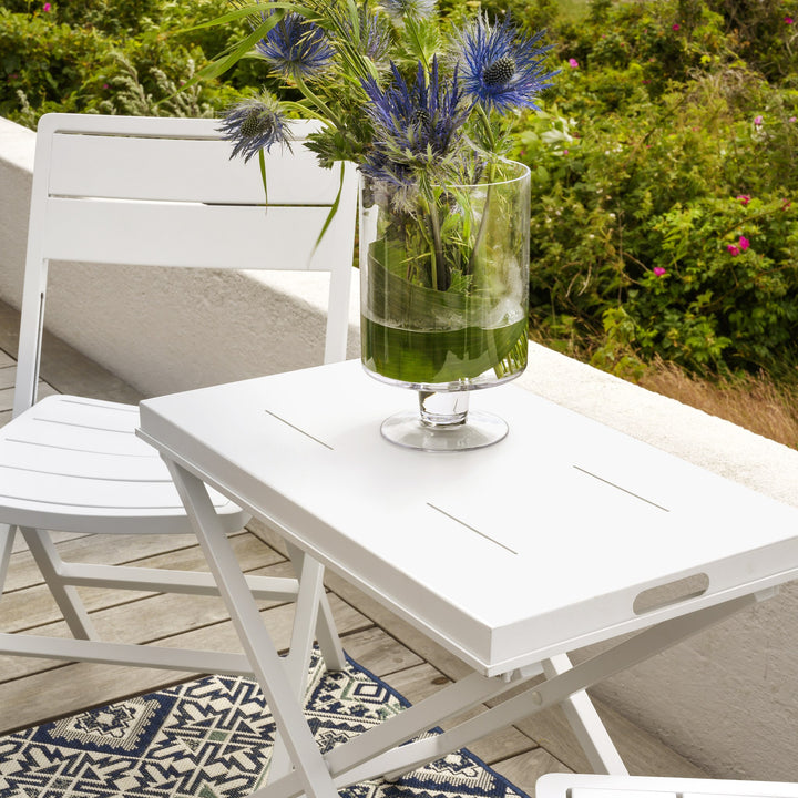 Brafab Wilkie klappstol i hvit ved klappbord med grønn vase og blå blomster på terrasse