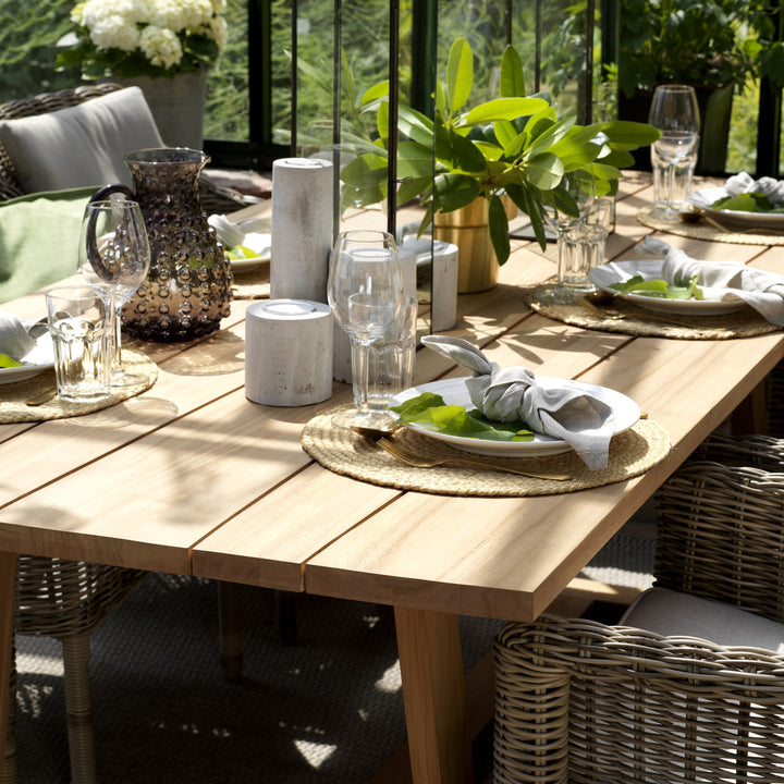 Brafab Lenora spisestol i kunstrotting ved dekket teakbord i lyst uterom med planter