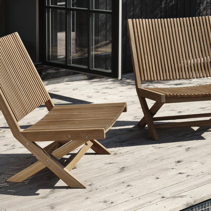 Brafab Julita hagestol i teak, to lave stoler på terrasse foran sort husvegg