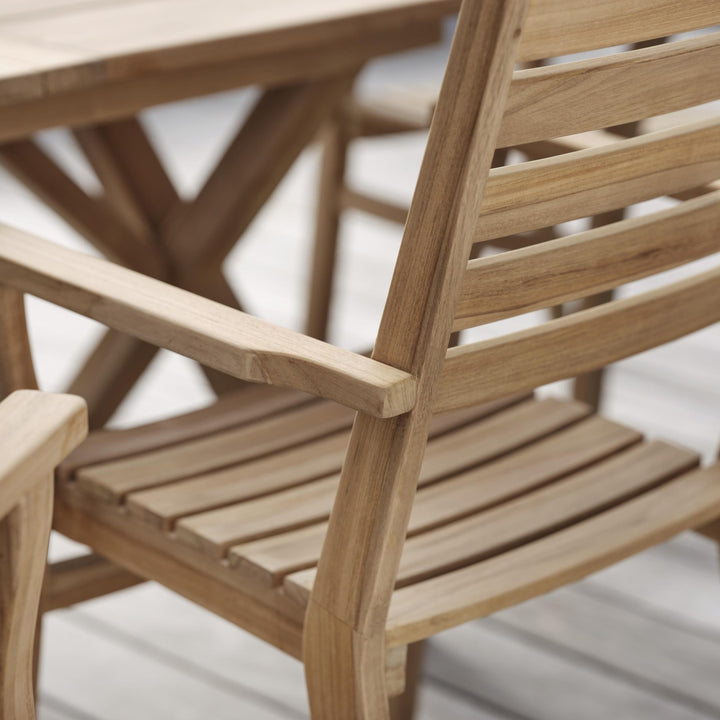 Brafab Keros spisestol i teak, nærbilde av armlene og rygg ved teakbord på terrasse