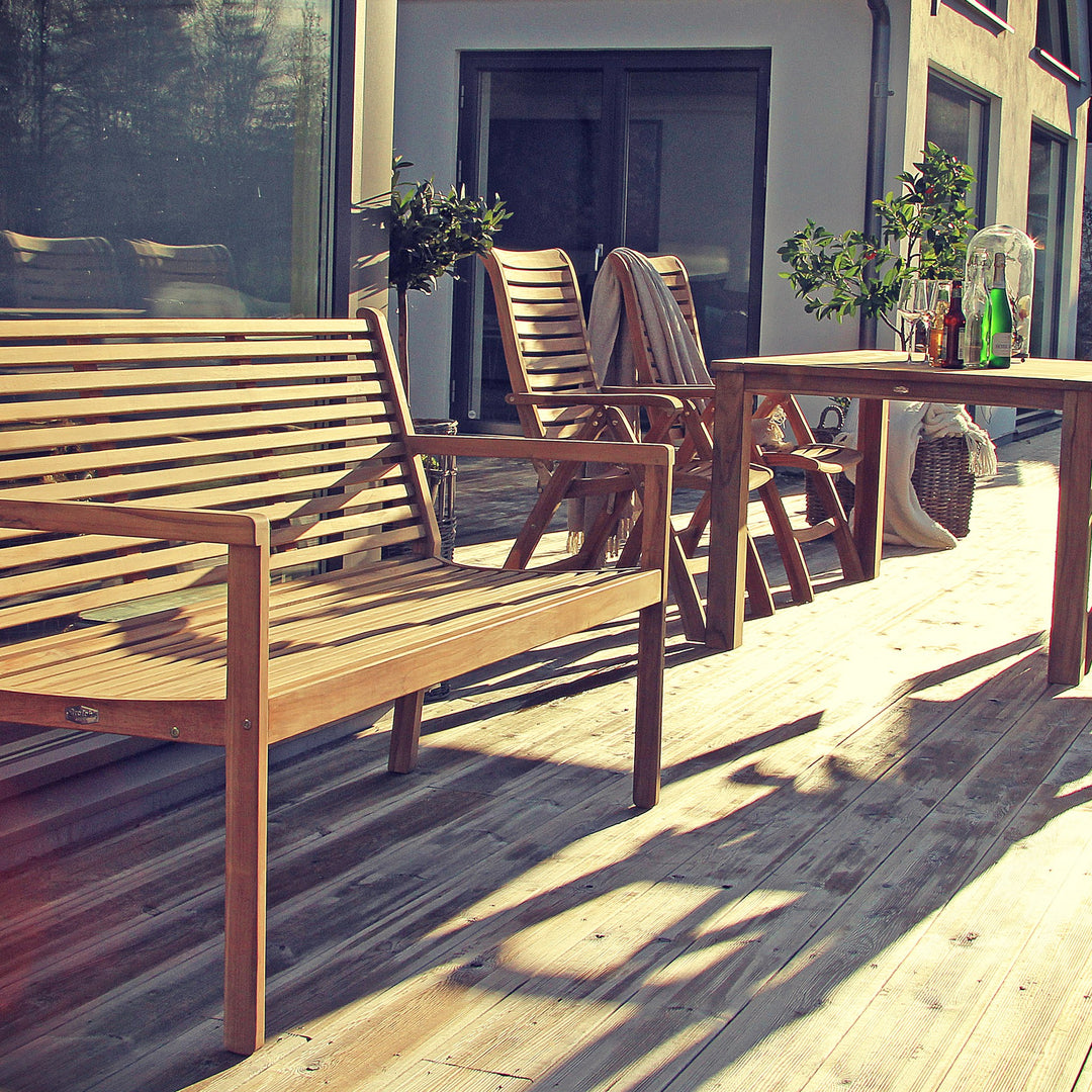 Brafab Canberra hagebenk i teak på solrik terrasse med stoler og bord