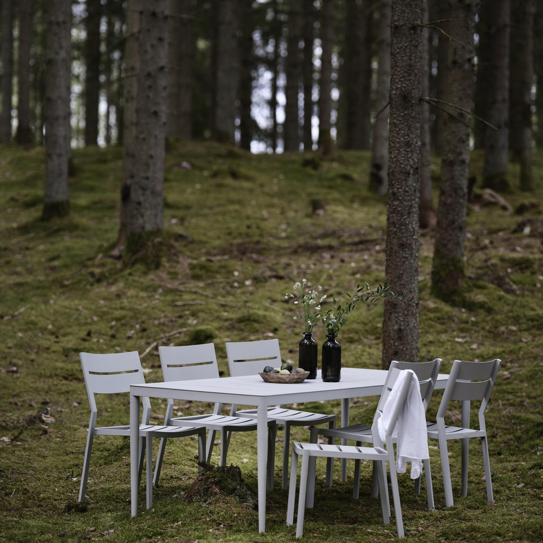 Brafab Delia spisestol uten armlene i lys grå, spisegruppe i skog med pledd over stol