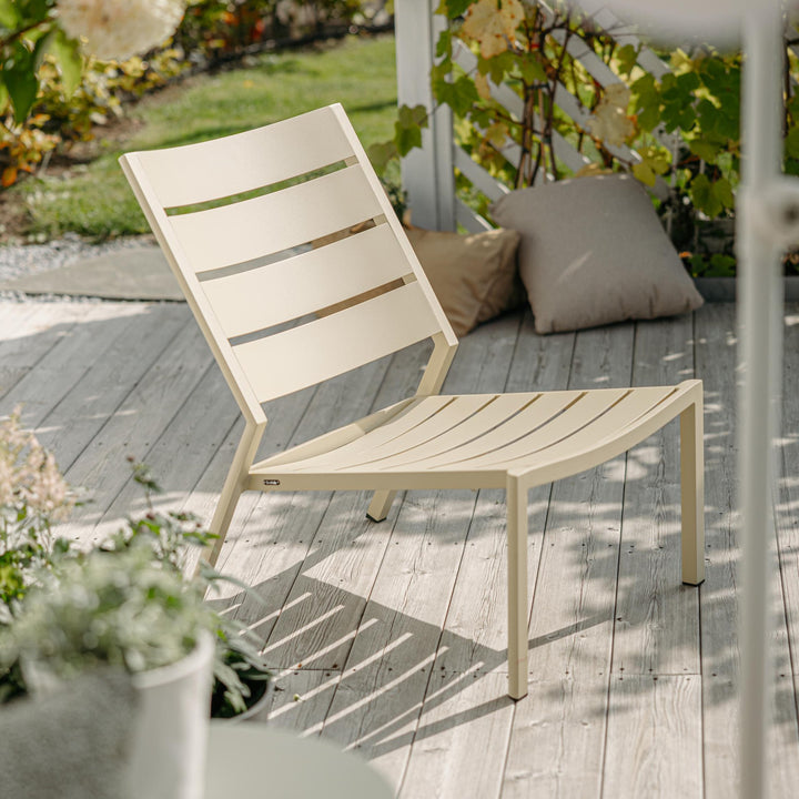 Brafab Delia loungestol i lys gul på terrasse med puter og grønne planter