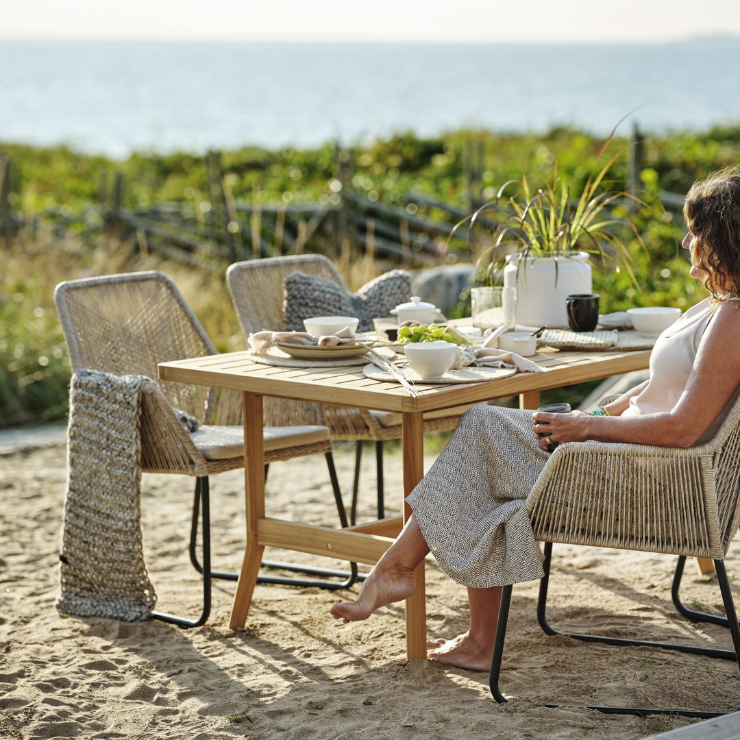 Brafab Midway spisestoler og teakbord på stranden ved sjøen med kvinne som sitter