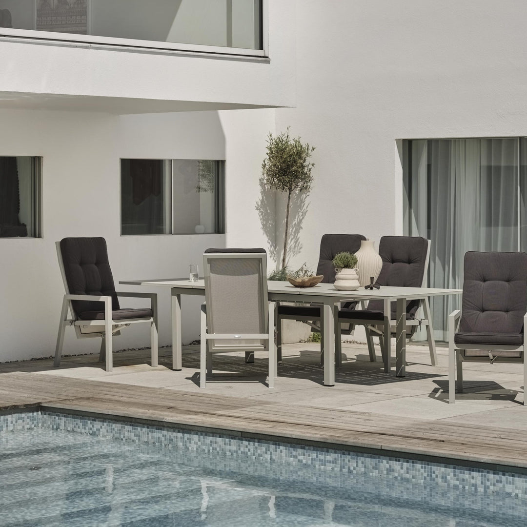 Brafab Newfort spisestol i lys grå rundt spisebord på terrasse ved basseng, med oliventre i krukke.