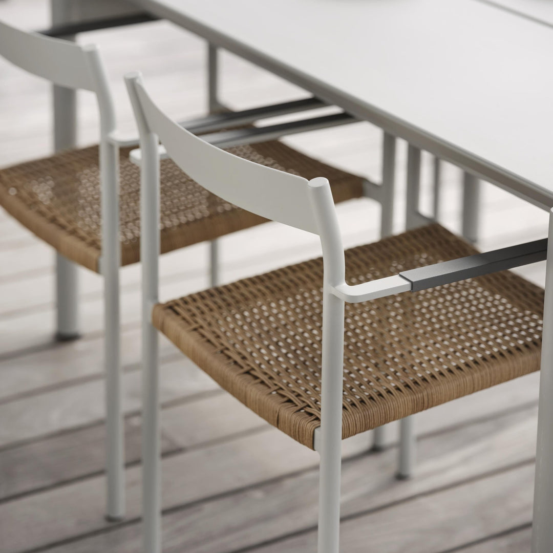 Brafab DK spisestol i lys grå med naturflettet sete ved bord på terrasse av tregulv