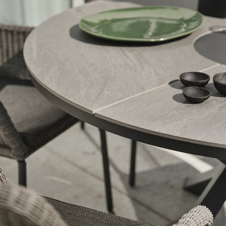 Brafab Dimma spisestol i lys grå kunstrotting ved dekket spisebord på terrasse