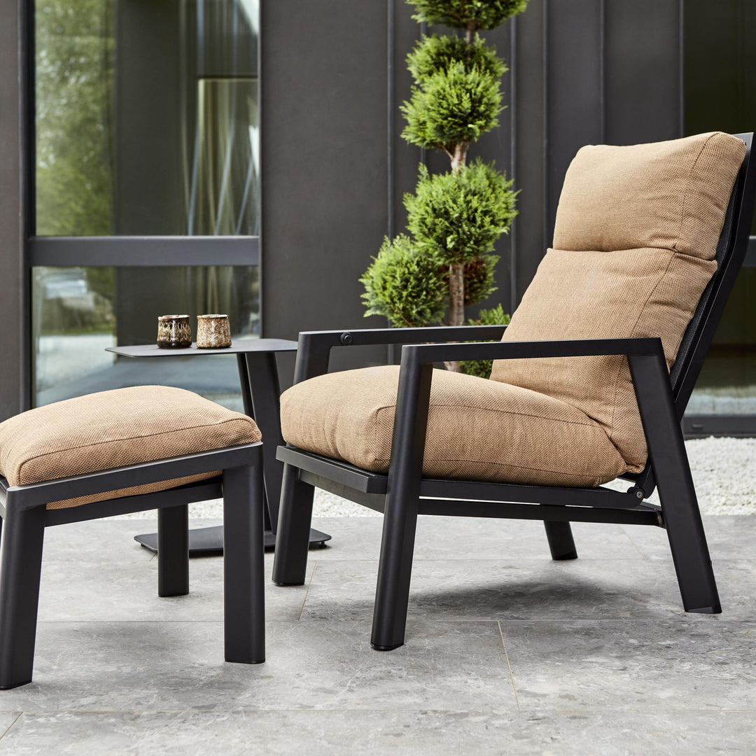 Brafab Slide fotskammel i sort med brun pute, med stol på terrasse
