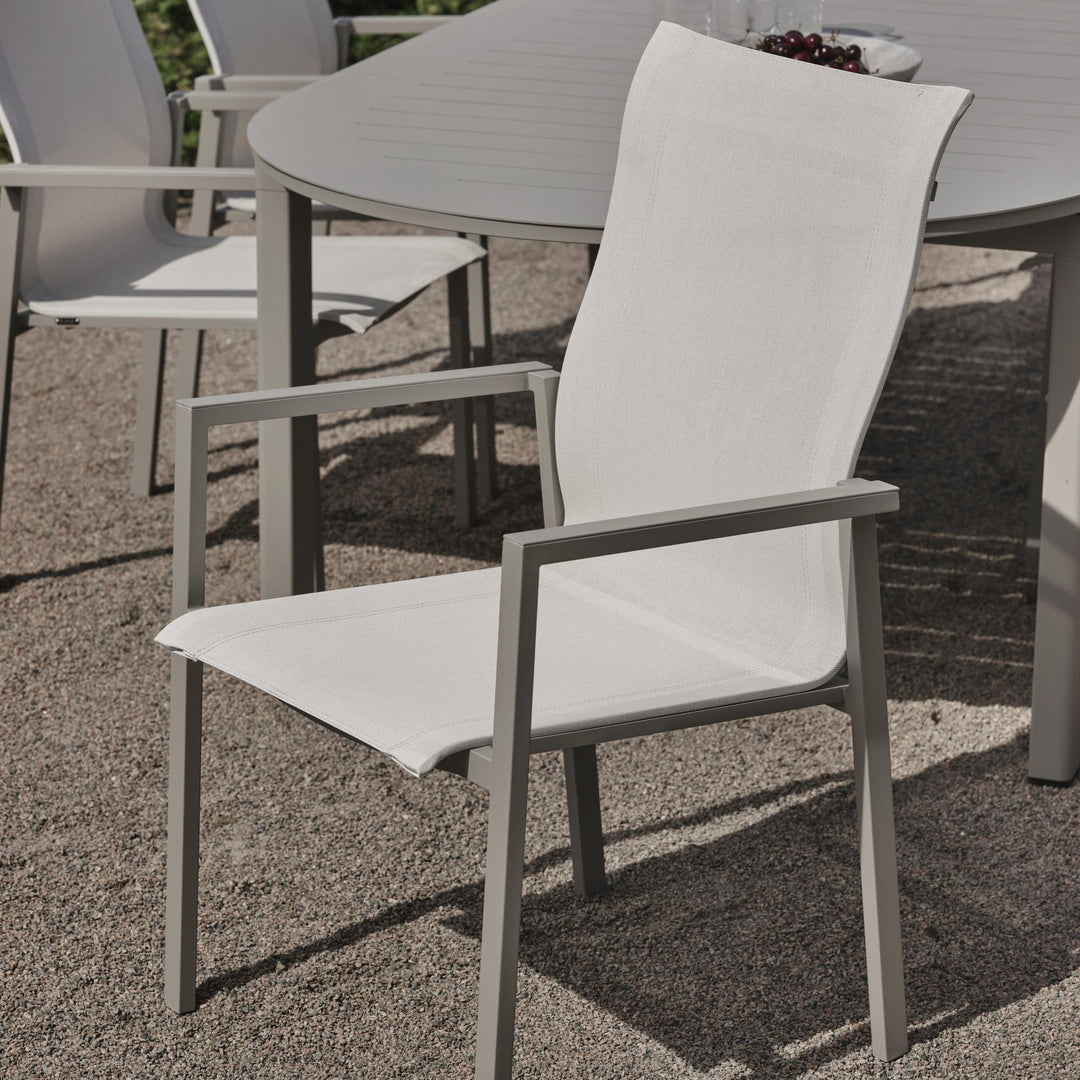 Brafab Comfy spisestol i offwhite tekstilén ved grått spisebord på grusterrasse ute