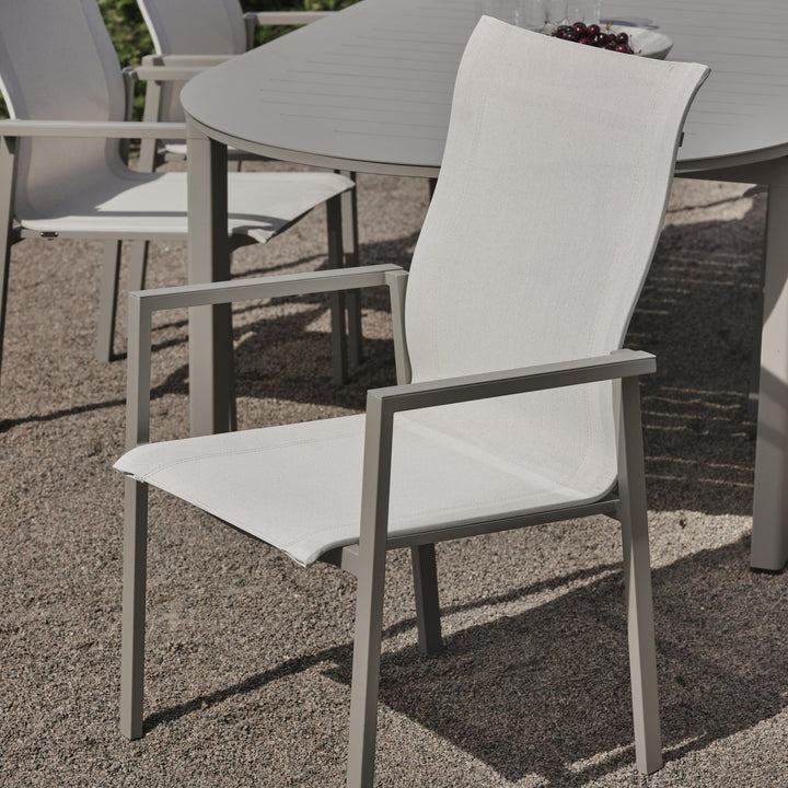 Brafab Comfy spisestol i offwhite tekstilén ved grått spisebord på grusterrasse ute